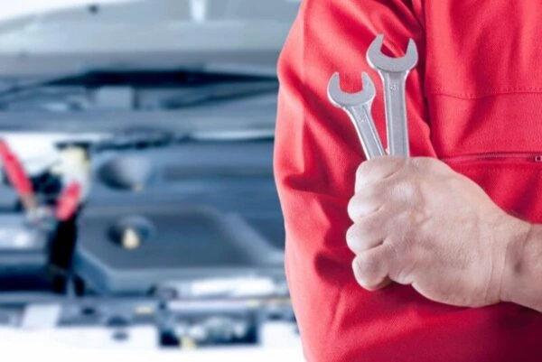 Automotive mechanic holding wrenches beside a vehicle recruited by Al Saqib Recruitment Agency