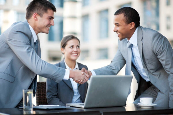 Business professionals shaking hands during a recruitment meeting arranged by Alsaqib Recruitment Agency.